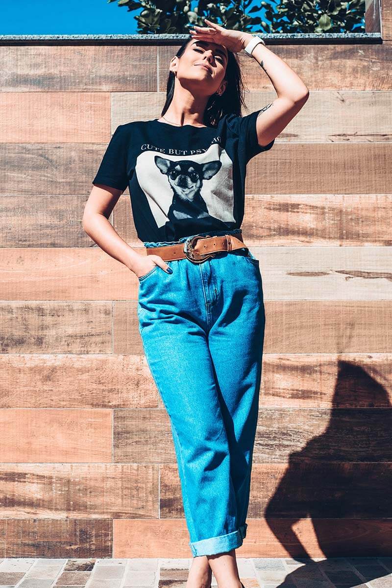Mulher vestindo calça jeans cintura alta com t-shirt com imagem de cachorrinho e usando cinto caramelo
